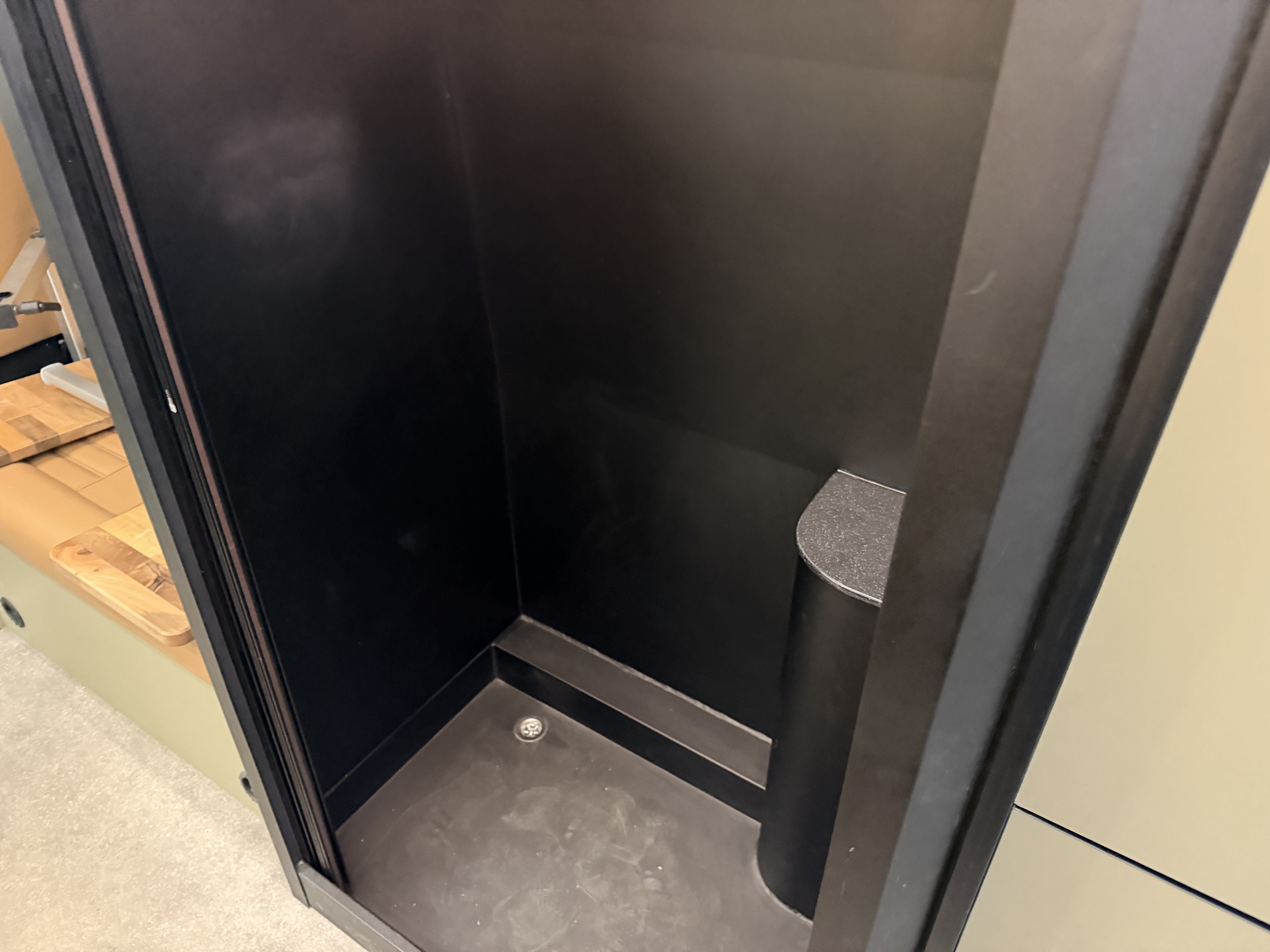 Greymatter 007 wet room — black composite shower cubicle with integrated chrome drain, built in-house