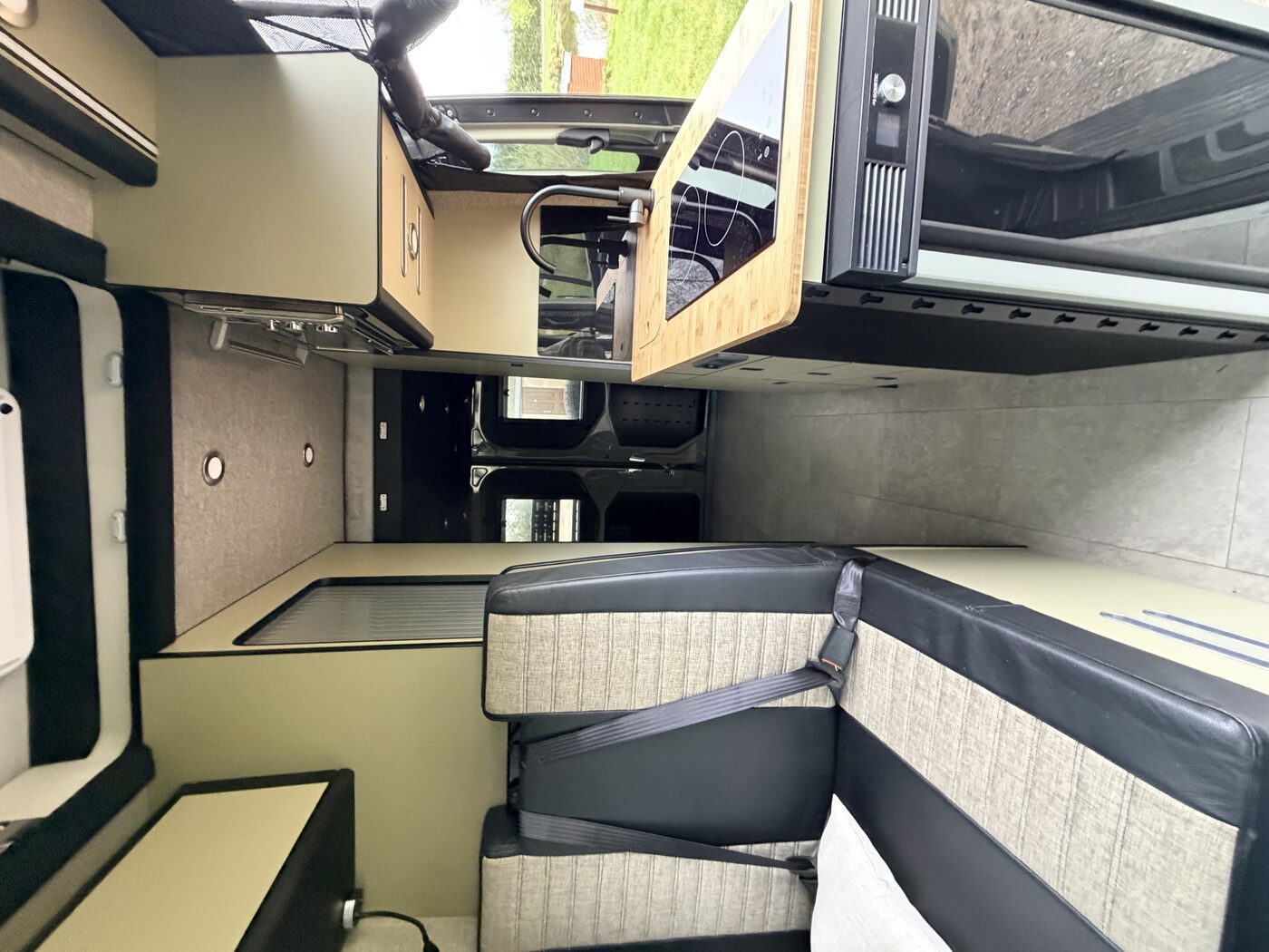 Ridgeline 002 Iron Trail interior — side longitudinal bed, compact galley kitchen and raw steel accent cabinetry